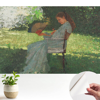 O femeie cu un ventilator în grădină simte armonie